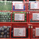 An assortment of different colored marbles in different drawers with glass fronts. There are price guides in British pounds.